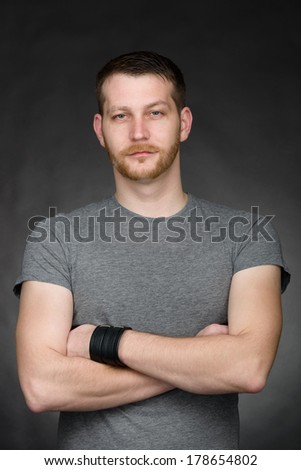 portrait of a young casual dressed student man with arms crossed against a dark background