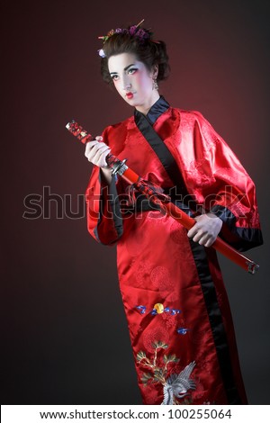 Young woman with flowers in her hair in red kimono and with sword