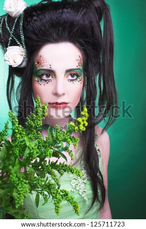 Spring fairy. Young woman in green dress and with artistic visage and hairstyle.