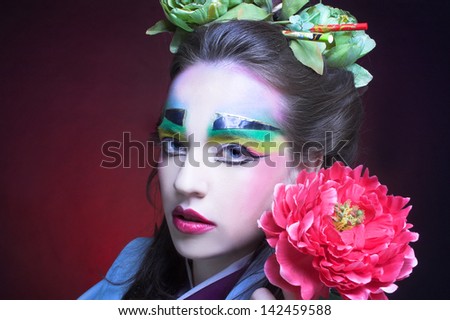 Young woman in creative image in eastern style with flowers in hair and in kimono.