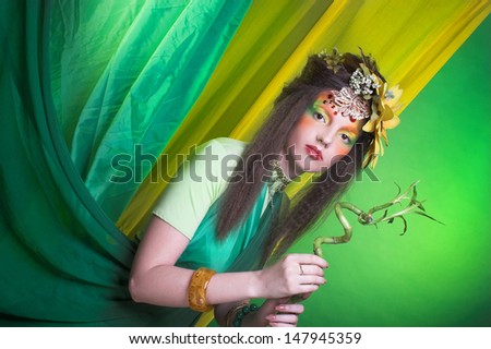 Fairy. Young woman in artistic image with flowers in her hair and with bamboo.
