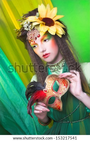 Fairy. Young woman in artistic image with flowers in her hair and with mask