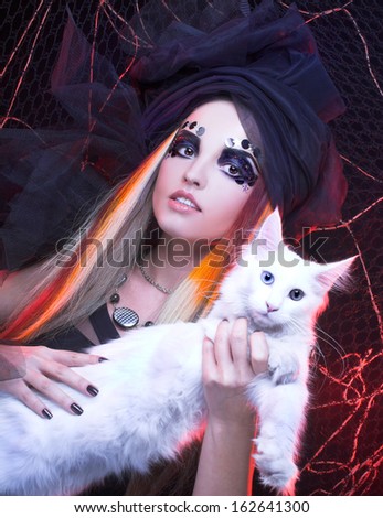 Gothic lady with artistic makeup posing witt white cat