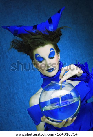 Creative young woman in  blue with sphere aquarium and brush in her hands