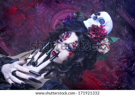 Young woman in witch image with bloody makeup ann with skull.
