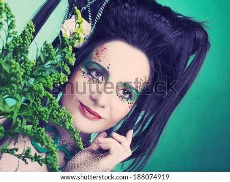 Spring fairy. Young woman in green dress and with artistic visage and hairstyle.