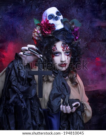 Halloween. Young woman in witch image with bloody makeup ann with skull.