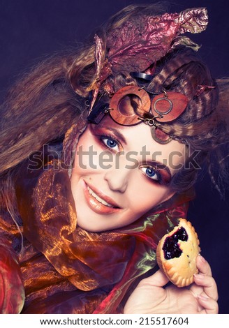 Young stylish lady with artistic make-up and autumn leafs in her hair and  with cake