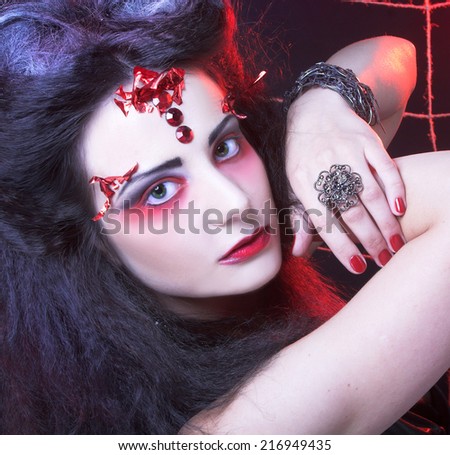 Halloween. Black widow. Young woman in dark artistic image posing with spider