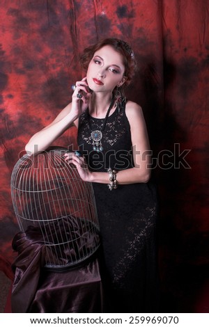 Portrait of young charming woman in ethnic image posing near cage.
