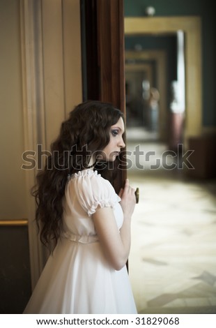 Dreaming young lady standing near opened door.