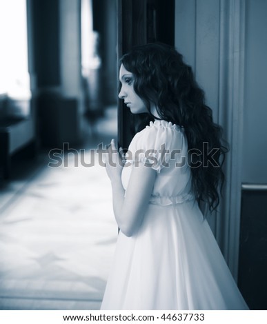 Dreaming young lady standing near opened door.