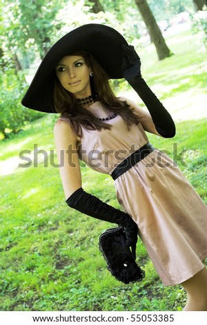 Young woman in black hat walking in the park. Retro style.