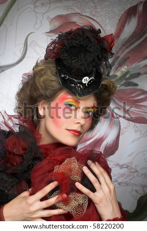Young lady in exotic little hat and with creative make-up.