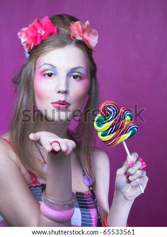 Portrait of young woman with lollipop and with pink flowers in her hair