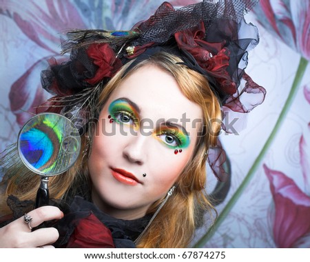 Creative lady in hat with feathers and with loupe.