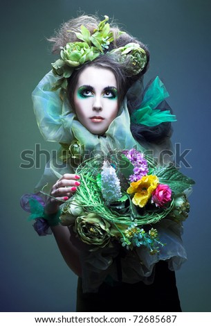 Young lady with artistic visage and with flowers in her hands and hair