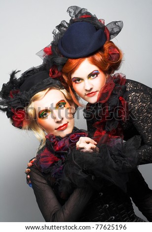 Two young ladies in vintage hats and corsets and with  artistic creative make-up