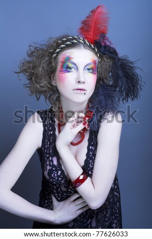 Young woman with  fashion creative visage and with feathers in her hair.