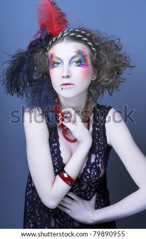 Young woman with  fashion creative visage and with feathers in her hair.