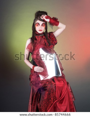 Sorceress. Lady in black and red dress and with fragment of mirror.