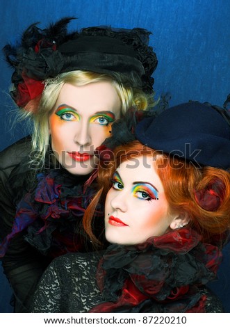 Two young ladies in vintage hats and corsets and with  artistic creative make-up.
