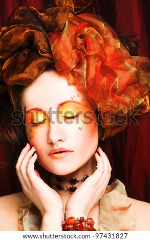 Young woman in creative image in retro style with orange and gold accessories