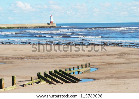 seascape of Spittal beach with wooden barrier, sea,waves,sand, with lighthouse