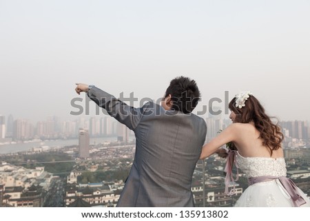 bride and groom standing  ouside with huangpu river, traditional Chinese wedding