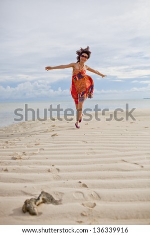 Chinese beauty is running with colorful one piece dress on the beach