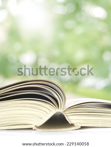 Open book, outdoors, close up,trees blurred in the background