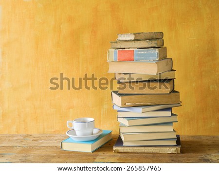 stack of books, with a cup of coffee on orange background, free copy space