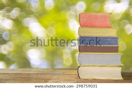 stack of books against blurred nature background, free copy space