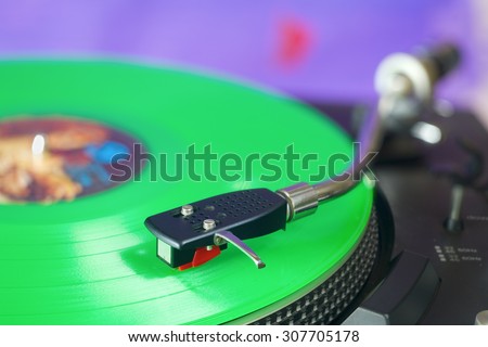 Retro turntable with green vinyl record, selective focus, fictional label artwork,free copy space