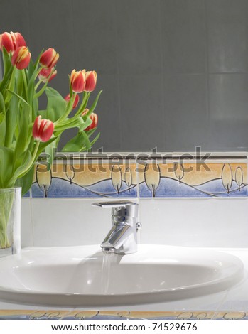 Working mixer tap with a few tulips on a counter
