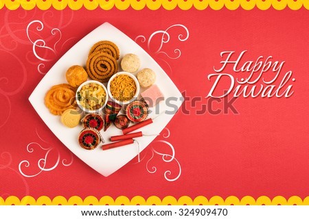 Diwali mithai like jalebi, bundi laddu, burfi and pera with Diwali snacks like chivda, sev, chakli served with Diwali firecrackers or fire crackers in a square white plate isolated on red background