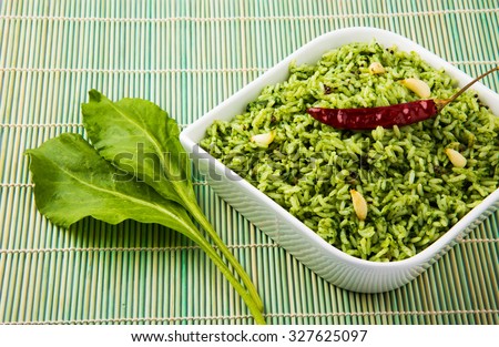 palak rice / spinach rice in a diamond shaped white ceramic bowl with raw spinach leaves on green mat