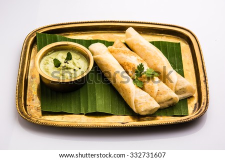 3 dosa rolls with coconut chutney in a brass tray over coconut leaf, favourite south indian meal,white background