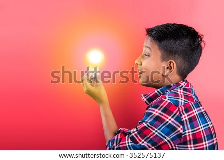 10 year indian boy holding glowing light bulb in hand, creativity concept, science concept, idea clicking expressions, indian boy, asian boy, side profile, red background