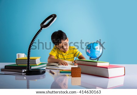 indian small boy studying or doing home work, asian boy studying with coffee mug, globe model and books on table
