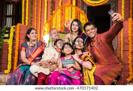 group photo of cheerful indian family in ganesh festival while taking selfie using smartphone , happy indian family and ganpati festival