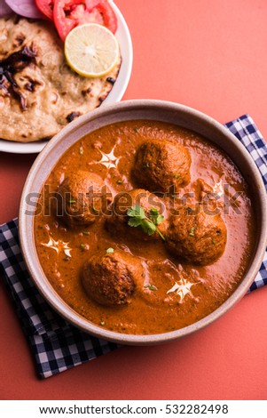 Freshly cooked spicy potato curry in frying pan or Hot and spicy Dum aloo served with tandoori roti or naan or indian bread or chapati and green salad, selective focus