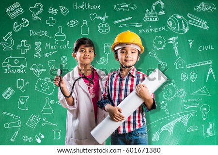 Kids and education concept - Small indian boy and girl posing in front of Green chalk board in engineers fancy dress with yellow helmet and doctor costume with stethoscope, wanna be engineer or doctor