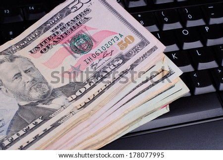 Close up of large amount of US currency laying on a computer keyboard