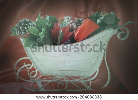 Christmas image of decorations piled in a decorative sleigh with copy space on the side of the sleigh with instagram effect applied