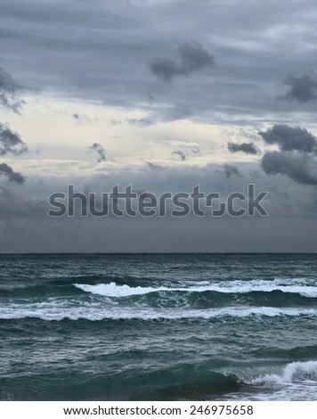 Very gloomy, overcast, cloudy sky over a dark stormy ocean.  While the waves are not huge, the presence of plenty of sea-form indicates the stormy conditions.  Vertical image of the Atlantic ocean.
