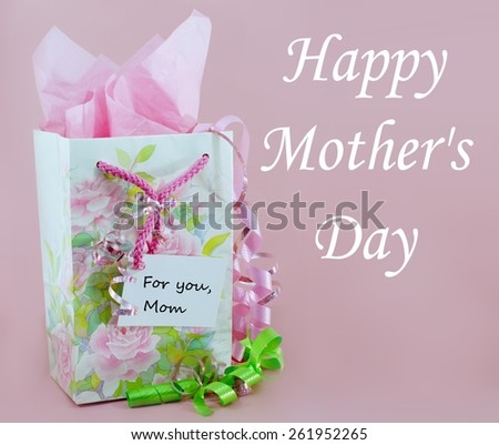 Pink and green are the main colors in Mother's Day gift bag decorated with spring flowers. Pink tissue paper is showing from inside the bag. There are matching pink and green ribbons and a message