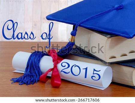 Graduation image of stacked books, diploma tied with red ribbon and blue graduation cap with tassel on wooden table. Class of 2015 message. Wood panel background.\
Books are very thick and seem old