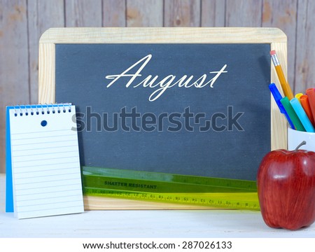 Month of the year with seasonally correct items placed around a blackboard with the month written across the top. There is a rustic wood background and copy space on the blackboard.
