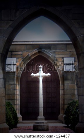 A view of a church yard in at dusk with light falling on a white cross that is viewed through an archway.  Vintage architecture frames the cross in front and behind. Slight amount of copy space above